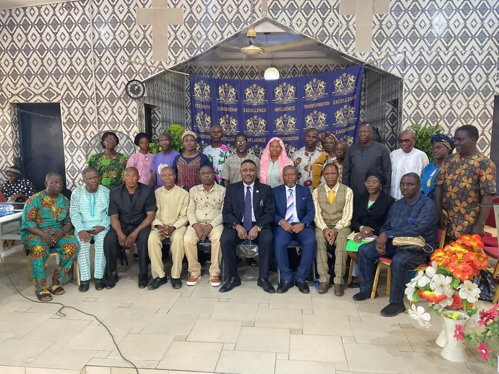 Large group photo of ministers and congregation members in front of the Abraham University banner
