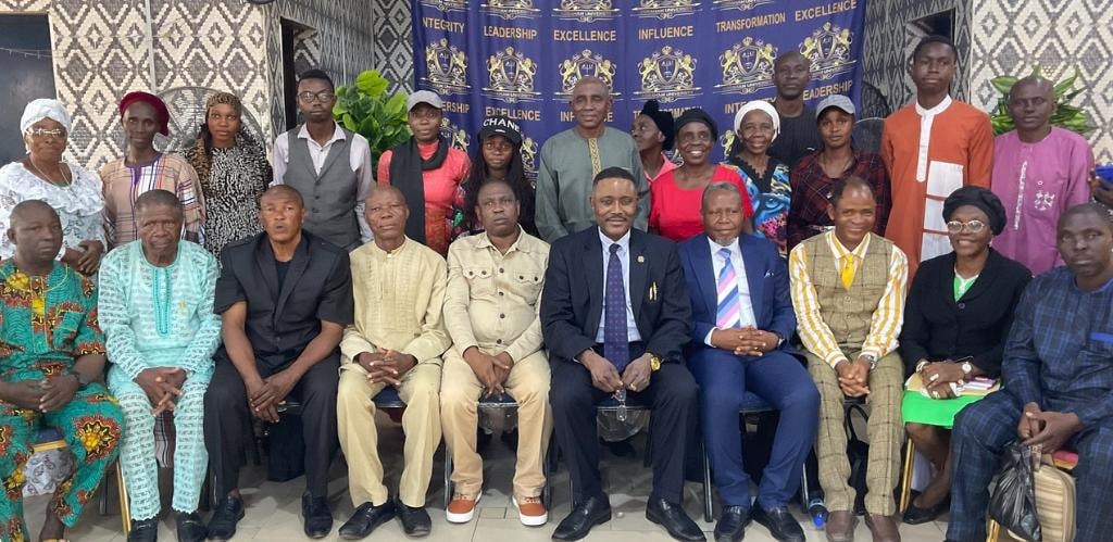 Group photo of congregation members and leaders in front of the Abraham University banner
